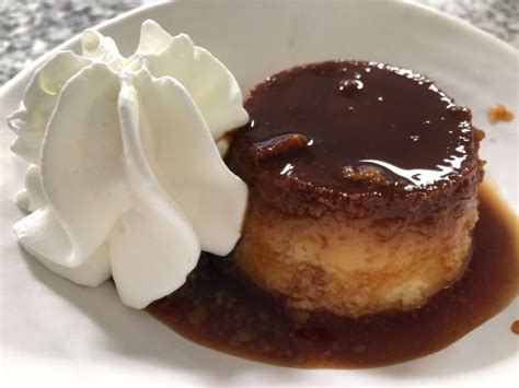 Flan con nata servido en un plato con una cucharilla de postre