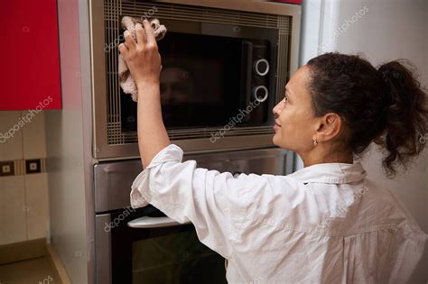 Mujer usando un microondas en una cocina moderna