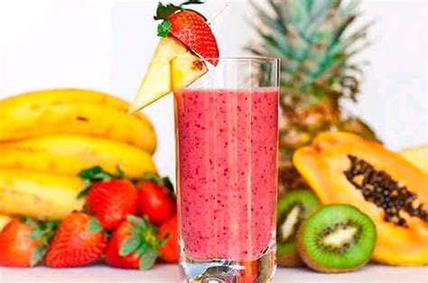 Imagen de un vaso de jugo surtido recién preparado con frutas alrededor