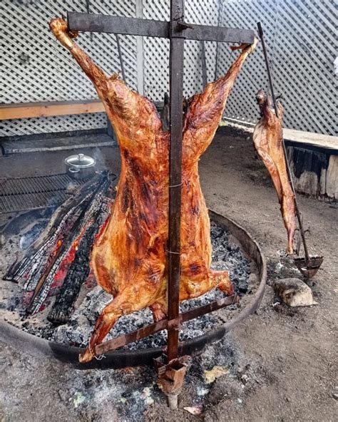 Cordero al palo asándose lentamente en el fuego