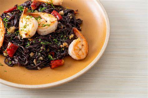 Plato de espaguetis negros preparados con mariscos y ajo