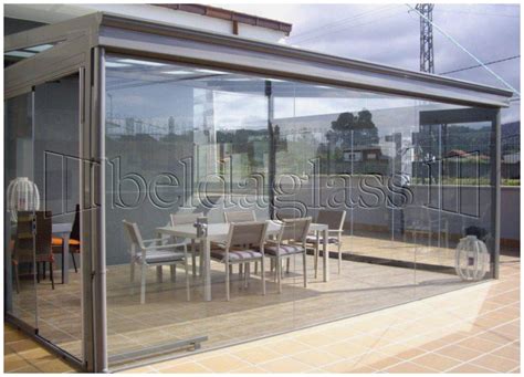 Terraza acristalada con barbacoa y cortinas de cristal abiertas