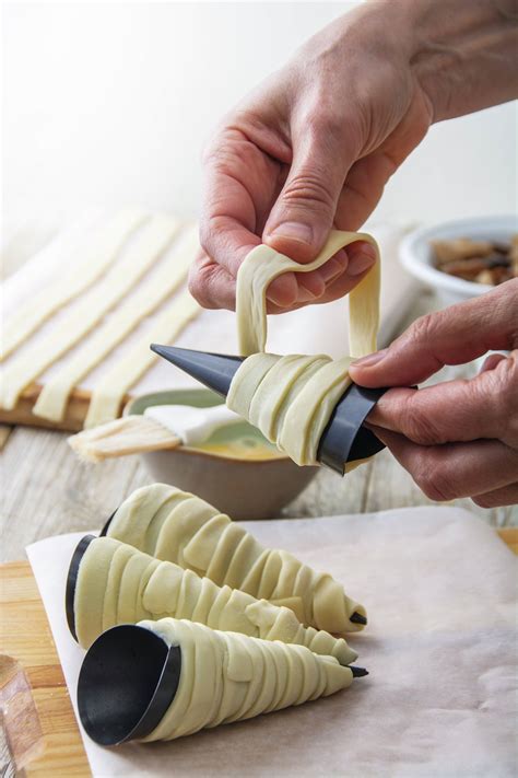 Proceso de enrollar tiras de hojaldre alrededor de rodajas de manzana