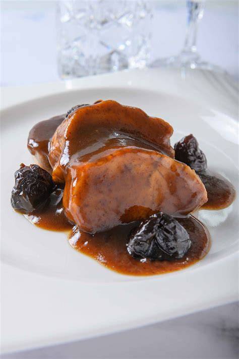 Solomillo de cerdo con ciruelas pasas y piñones en un plato servido