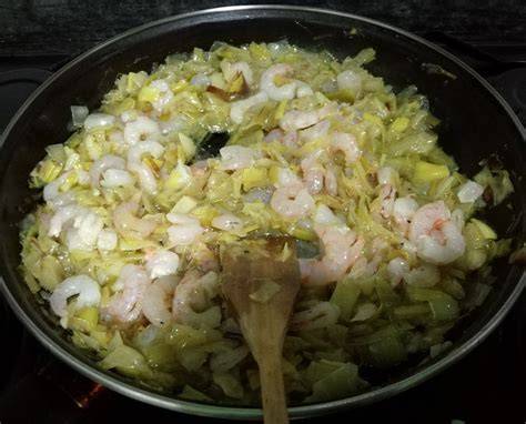 Puerros y gambas rehogándose en una sartén