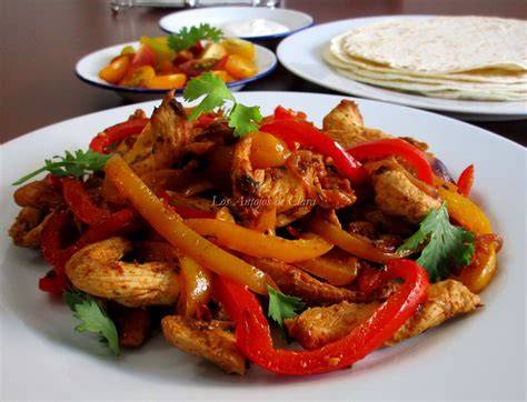 Plato de fajitas de pollo con tortillas y guarniciones