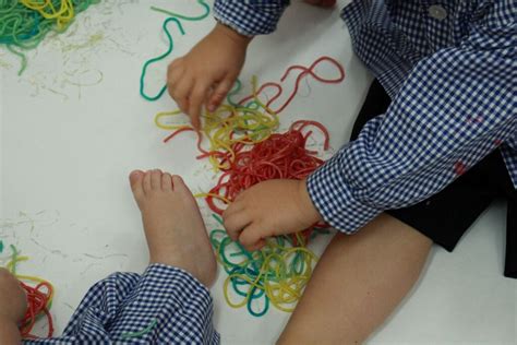 niños jugando con espaguetis de colores en un taller sensorial