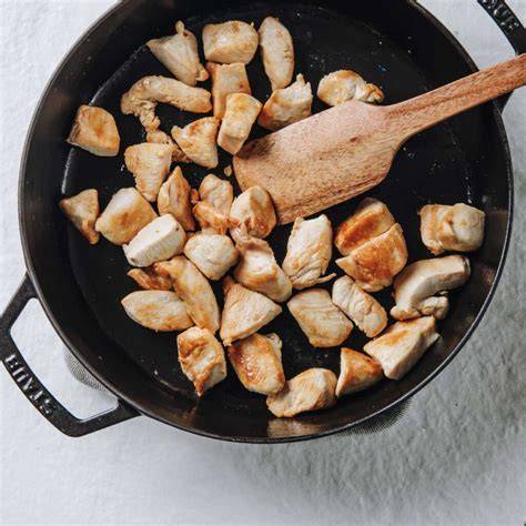 Sartén con aceite caliente y trozos de pollo dorándose