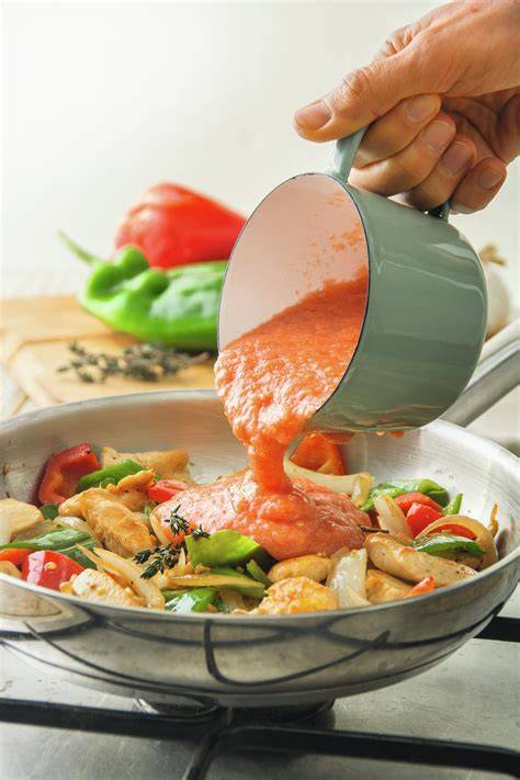 Sartén con pollo, cebolla, ajo y salsa de naranja burbujeando