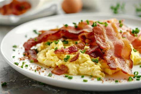 Plato de huevos revueltos con tocino crujiente y tostadas