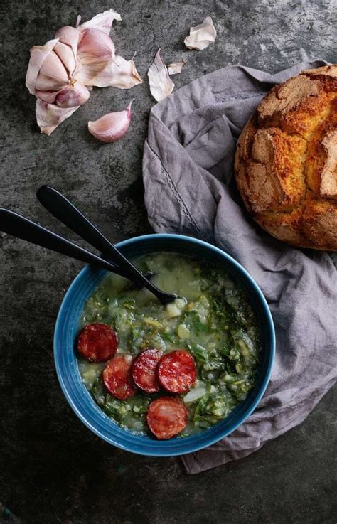 Caldo verde portugués servido en un cuenco con pan de maíz y una copa de vino