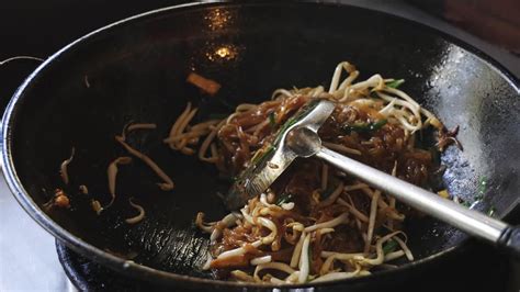 Chef salteando fideos udon en un wok