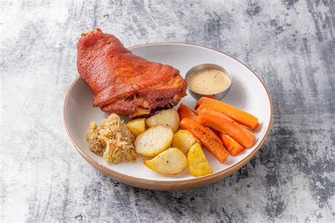 Codillo de cerdo cocinado servido en plato con guarnición