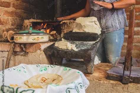 Mujer mixteca elaborando tortillas de maíz en un metate y comal
