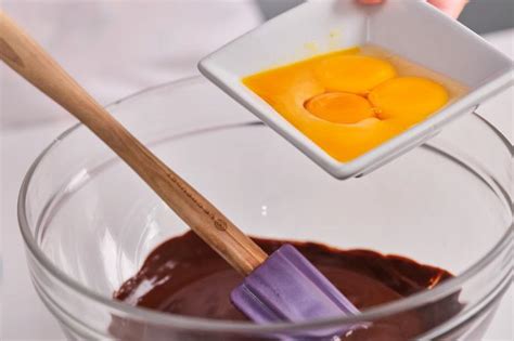 Mezcla de chocolate hirviendo sobre las yemas de huevo