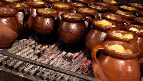 Pucheros individuales cocinándose a fuego lento sobre brasas