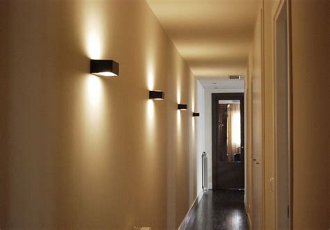 Pasillo moderno con iluminación indirecta y apliques de pared