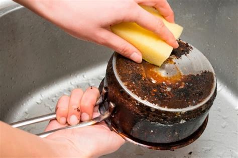 Mano espolvoreando sal en el fondo de una olla quemada
