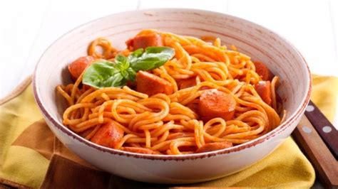 Una imagen de espaguetis con salchichas y crema en un plato