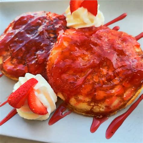 Tortitas de fresa sobre un plato con sirope y fresas frescas