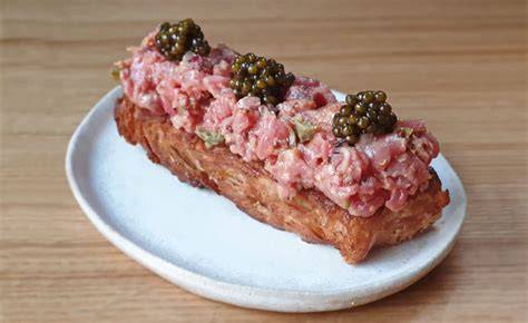 Plato elegante de steak tartar con caviar sobre base crujiente