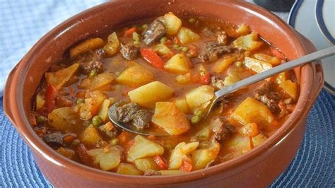 Plato tradicional de carne richada servido en barro con pimientos y patatas