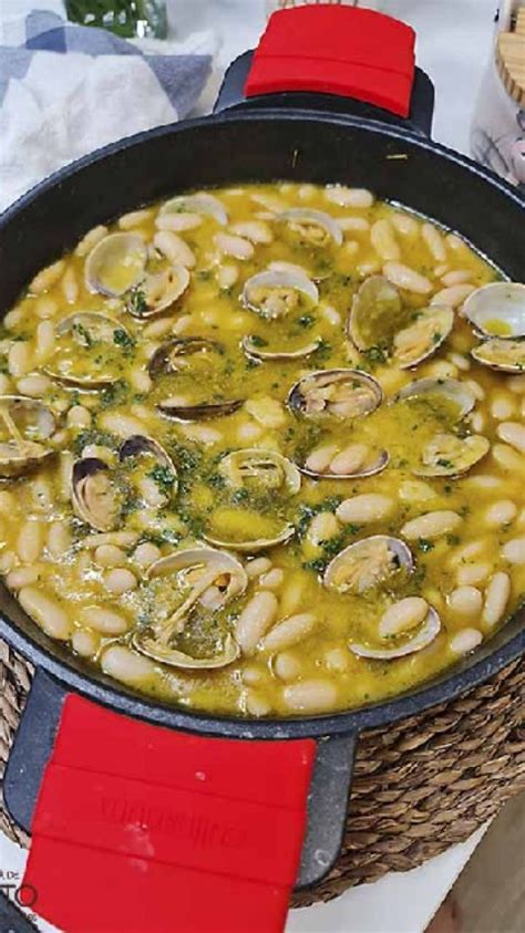 Primer plano de almejas abriéndose en una cacerola con sofrito