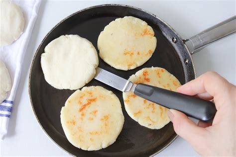 Arepas dorándose en una sartén caliente