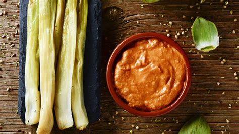 Persona comiendo calçots con salsa romesco