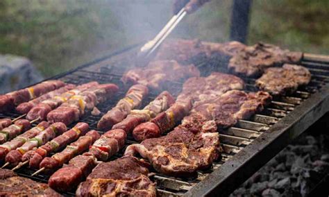 Barbacoa de gas encendida con diferentes tipos de alimentos cocinándose