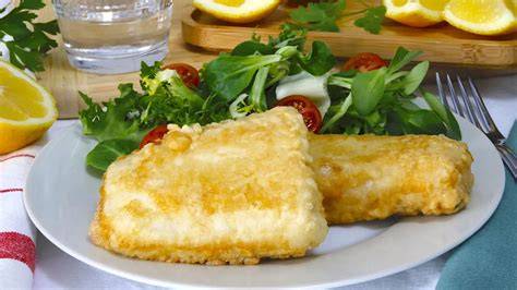 Merluza a la romana en un plato con limón