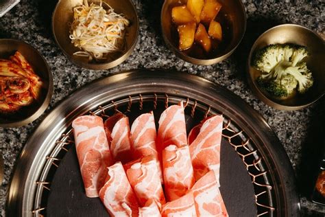 Ilustración de una mesa de barbacoa coreana con diferentes cortes de carne y acompañamientos