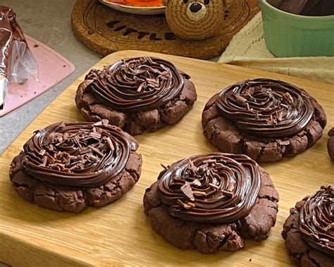 Crumbl Cookies de chocolate decoradas con betún y chocolate rallado