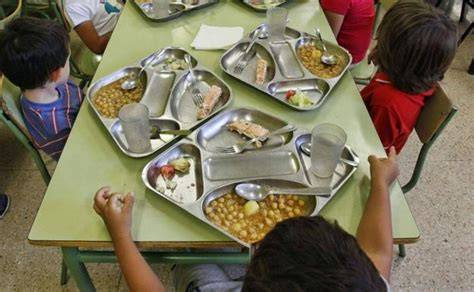 Niños disfrutando de paella en el comedor escolar