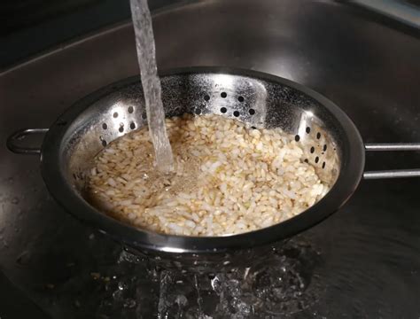 Arroz en colador bajo el grifo