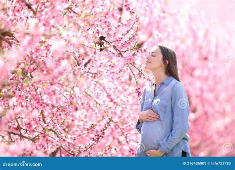 Mujer embarazada oliendo flores