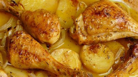 bandeja de horno con pollo rodeado de patatas y cebollas