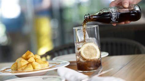 Persona añadiendo una rodaja de limón a una Coca-Cola