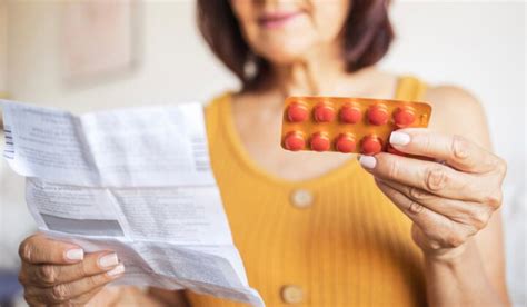 Mujer leyendo el prospecto de un medicamento con una botella de Coca-Cola al lado