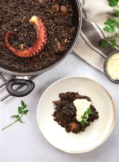 Plato de arroz negro con chocos servido en cazuela tradicional