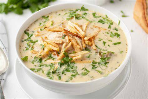 Sopa de maní con pollo servida con papas fritas y un plato pequeño de llajua