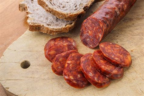 Rodajas de chorizo curado sobre una tabla de madera con pan