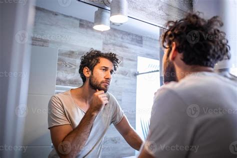 Hombre joven preocupado por la caída del cabello mirándose al espejo