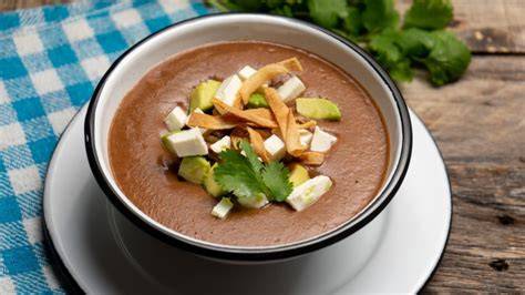 Sopa de frijol servida con crema y aguacate