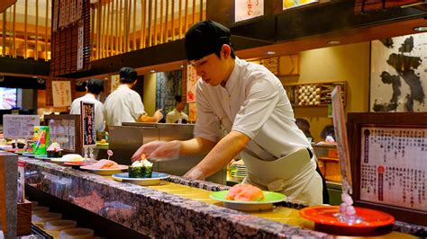 Interior de un restaurante de sushi en cinta transportadora con clientes disfrutando