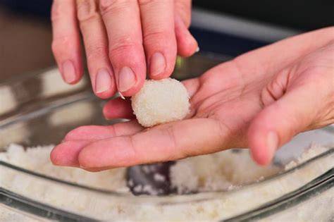 Manos formando bolitas de coco a partir de la mezcla