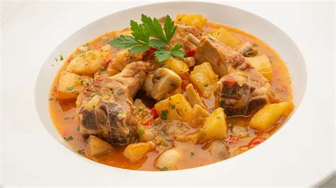 Cordero guisado servido con patatas fritas y hierbas frescas