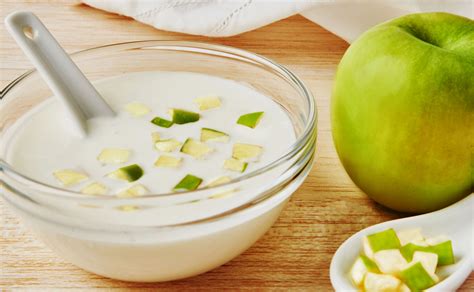 Manzanas frescas con un cuenco de yogur natural y canela sobre una mesa de madera
