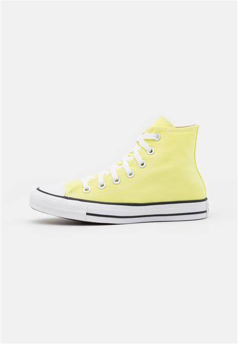 Zapatillas Converse de color amarillo pastel sobre un fondo neutro