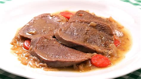 Plato de lengua de res guisada con salsa de tomate y acompañamiento